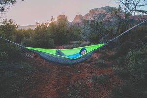 A man sitting in a neon green hammock.