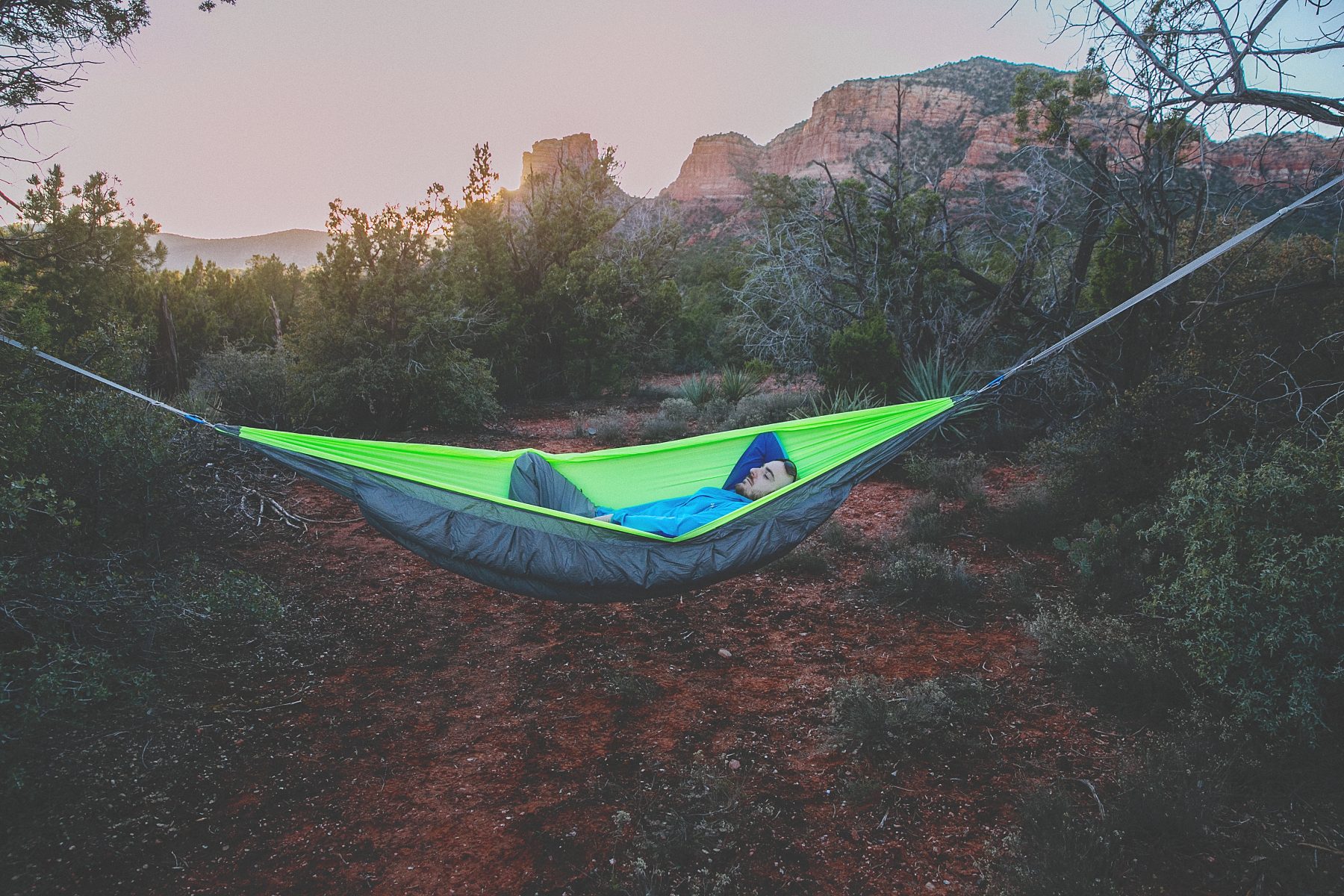 A man sitting in a neon green hammock.