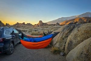 Orange, blue and camo hammock set up in the desert.